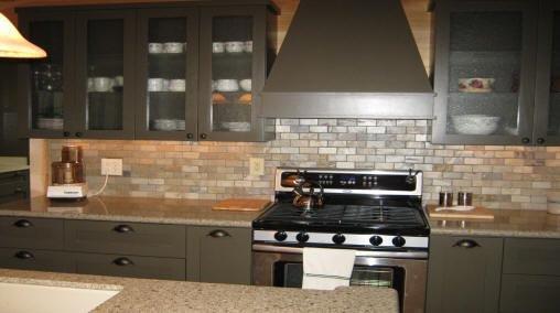 Finished kitchen 3 - Stone backsplash behind stove, stove hood venting to the outside and gray cabinets.