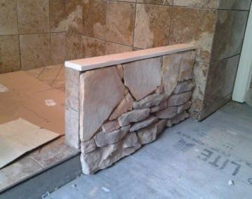 Tile installed at interior of shower and stone installed at exterior wall.